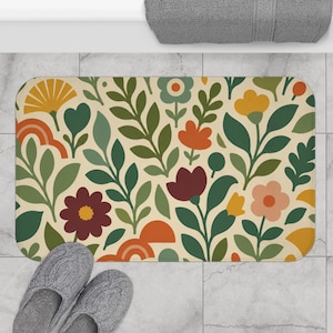 May include: A rectangular bath mat featuring a repeating pattern of stylized flowers and leaves in shades of dark red, orange, yellow, and various greens on a cream background. The design includes rounded shapes and organic botanical motifs.
