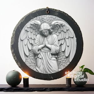 May include: A round slate plaque with a 3D sculpted image of a praying angel with wings. The angel is white and the background is black.