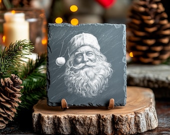 May include: A black slate coaster with a white and gray image of Santa Claus. The coaster is on a wooden stand.