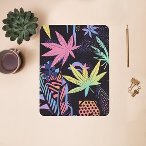 May include: A black background with a colorful pattern of marijuana leaves. The leaves are in shades of pink, blue, green, and yellow. The background is dotted with small white dots.