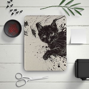 May include: A black cat with white markings on its face peeks out from a splatter of black paint on a white background.