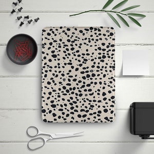 May include: A beige and black desk mat with a dalmatian print. The mat is rectangular and has a smooth surface.