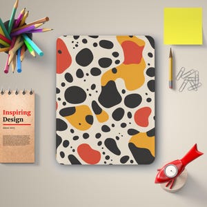 May include: A white background with a pattern of black, orange, and red abstract shapes. The pattern is reminiscent of a dalmatian dog's spots.
