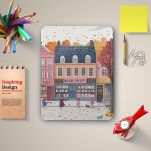 May include: A digital illustration of a book shop with a pink and yellow facade. The shop is located on a street with people walking by and autumn leaves falling from the trees. The shop sign reads "BOOK SHOP".