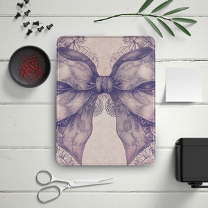 May include: A purple and white patterned digital tablet case with a large bow design.