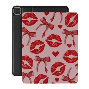 May include: A pink and red iPad case with a pattern of red lips and hearts. The case has a black leather flap on the back.