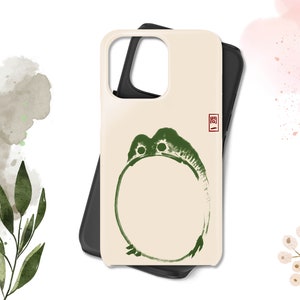 May include: A cream-colored phone case with a green frog design and a red seal with the character "関" in Japanese. The case is made of a hard plastic material and has a matte finish.