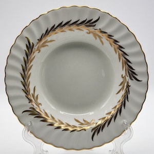May include: A white ceramic bowl with a gold and black leaf design around the rim.