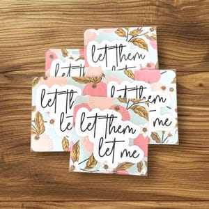 Puede incluir: Un conjunto de cinco tarjetas cuadradas con un patr&oacute;n floral y el texto "Let them let me" en escritura cursiva negra. Las tarjetas tienen un fondo azul claro con acentos rosados y dorados.