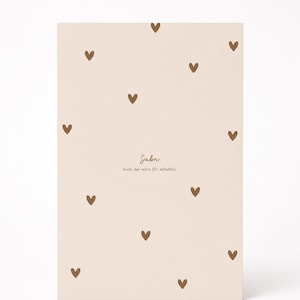 Könnte beinhalten: Eine beige Karte mit verstreuten braunen Herzformen. Die Karte trägt den Namen "Sabn" in einer handschriftlichen Schriftart sowie den Satz "Auch das wirst DU schaffen". Das Design ist schlicht und elegant.