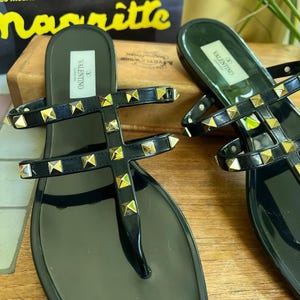 Y2K Valentino Garavani Rockstud Jelly Sandals - Black PVC Thong Flip Flops - Women's Size 40 US 10 - Studded Shoes Made in Italy

Edgy sophistication to your summer wardrobe!
Valentino Garavani Rockstud Jelly Sandals. A cult favorite in the Valentino lineup, these sandals combine the effortless ease of a jelly flip-flop with the high- fashion impact of the iconic pyramid Rockstuds.

Premium high-shine black PVC, these sandals feature the
signature silver-tone studs along the straps.