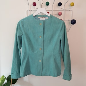May include: A teal blue suede blazer with a mandarin collar and five button closures. The label reads "Halston, ImagiN",