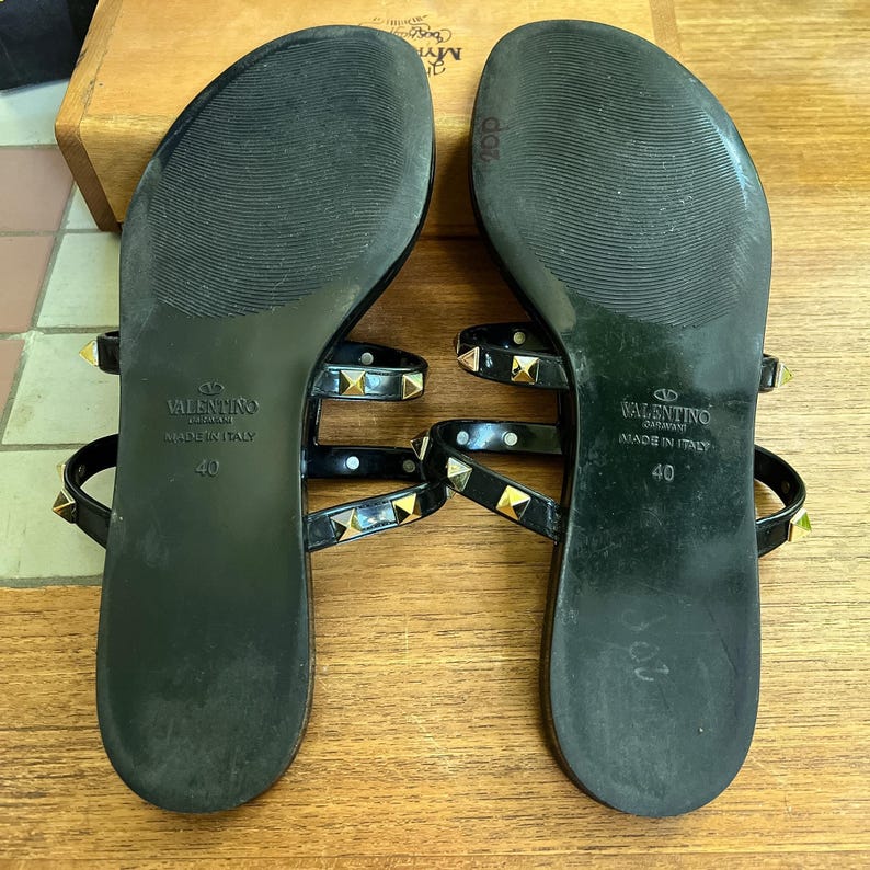 Y2K Valentino Garavani Rockstud Jelly Sandals - Black PVC Thong Flip Flops - Women's Size 40 US 10 - Studded Shoes Made in Italy

Edgy sophistication to your summer wardrobe!
Valentino Garavani Rockstud Jelly Sandals. A cult favorite in the Valentino lineup, these sandals combine the effortless ease of a jelly flip-flop with the high- fashion impact of the iconic pyramid Rockstuds.

Premium high-shine black PVC, these sandals feature the
signature silver-tone studs along the straps.