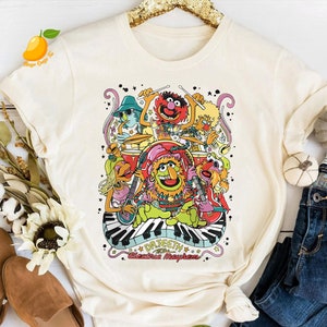 May include: A white t-shirt with a colorful graphic of the Muppets playing instruments. The graphic includes the text "Dr. Teeth & The Electric Mayhem".