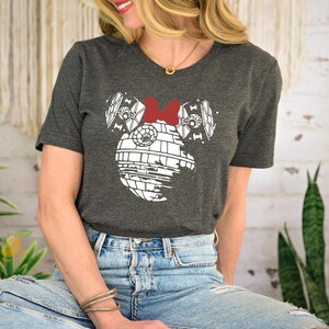 a woman sitting on a stool wearing a mickey mouse shirt