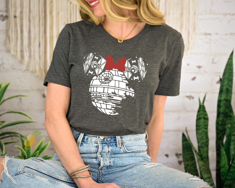 a woman sitting on a stool wearing a mickey mouse shirt