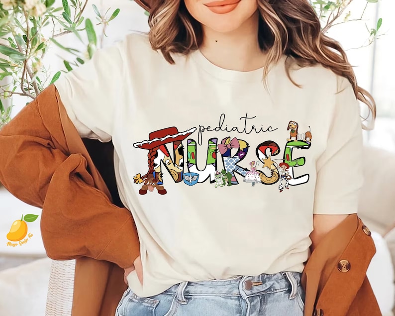 May include: White t-shirt with a graphic of the word "NURSE" made up of characters from the Toy Story movie franchise. The word "pediatric" is written above the graphic.