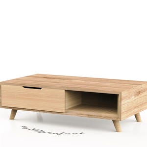 May include: A light wood coffee table with a drawer and a shelf. The table has a simple, modern design with tapered legs.