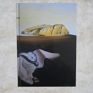 Puede incluir: Un libro de tapa dura con una pintura surrealista. La portada muestra un reloj derritiéndose sobre una forma, con un paisaje desértico y una montaña al fondo. La paleta de colores incluye marrones, beiges y negros.
