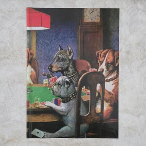 Puede incluir: Un cuaderno con una ilustración vintage de perros jugando al póquer. La imagen muestra perros sentados alrededor de una mesa de póquer, fumando cigarros y bebiendo. El fondo incluye un reloj de pie y una lámpara roja.