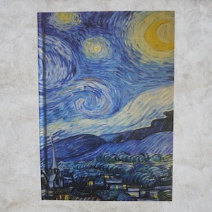 Puede incluir: Un cuaderno rectangular con una impresión de "La noche estrellada" de Vincent van Gogh. La portada muestra el famoso cielo azul y amarillo arremolinado, con una escena de pueblo en la parte inferior. El cuaderno tiene orientación vertical.