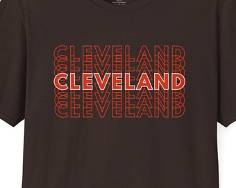 May include: A brown t-shirt with a stacked graphic print of the word "CLEVELAND" in red and orange.