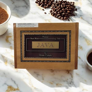 May include: A wooden box with a gold label that reads "Premium Hand Made Long Filler JAVA by Drew Estate". The box is sitting on a marble surface with coffee beans scattered around it.