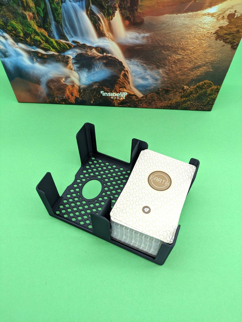 May include: A black card holder with a deck of cards inside. The cards have a white background with a gold circle that says "EARTH".