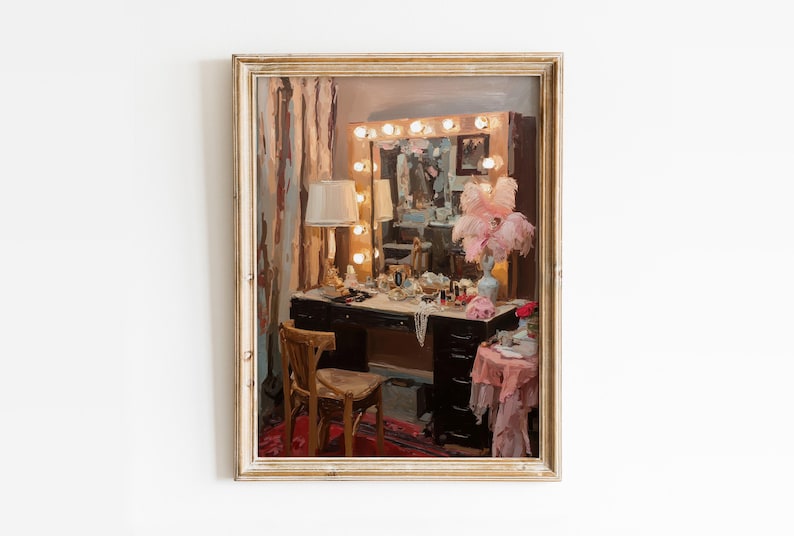 May include: A framed painting depicts a vintage vanity scene. A dark wood vanity table is adorned with makeup, jewelry, and a lamp. A mirror with light bulbs is above the table. A wooden chair sits in front of the vanity, and a pink table with a vase of pink feathers is to the side.