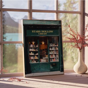 Op de afbeelding: Een groen gebouw met een bord waarop "Stars Hollow Library" staat. Het gebouw heeft grote ramen met boekenkasten erin. Het gebouw is in een donkergroene kleur geverfd met witte accenten.