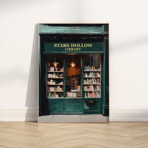 Op de afbeelding: Een groene winkelgevel met een bord waarop "Stars Hollow Library" staat. De winkelgevel heeft een groot raam met boekenkasten vol boeken. Het raam wordt verlicht door twee lampen.