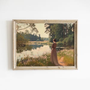 May include: A framed oil painting depicting a woman in a brown dress standing by a lake in a woodland setting. The lake is surrounded by trees and wildflowers. The sky is a light blue with a few clouds.