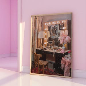 May include: A framed painting of a vanity table with a lighted mirror, a lamp, and various beauty products. A wooden chair sits in front of the table. The painting has a vintage aesthetic, with soft pink and brown tones. A vase with pink feathers is on the table.
