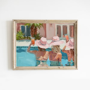 May include: Three women in pink sun hats are sitting in a swimming pool, holding cocktails. The pool is surrounded by a pink and white building with palm trees in the background.