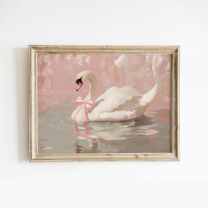 Puede incluir: Una pintura enmarcada de un cisne blanco con un lazo rosa en el cuello, nadando en un lago con un fondo rosa y gris.