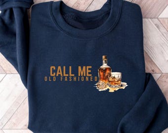 May include: Navy blue sweatshirt with the text "CALL ME OLD FASHIONED" in brown lettering. A drawing of a bottle of whiskey and a glass of whiskey with ice cubes is on the sweatshirt.