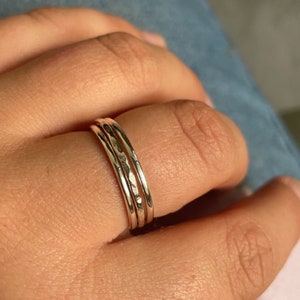 Pode incluir: Tr&ecirc;s an&eacute;is finos de prata empilhados em um dedo. Os an&eacute;is t&ecirc;m uma textura martelada.