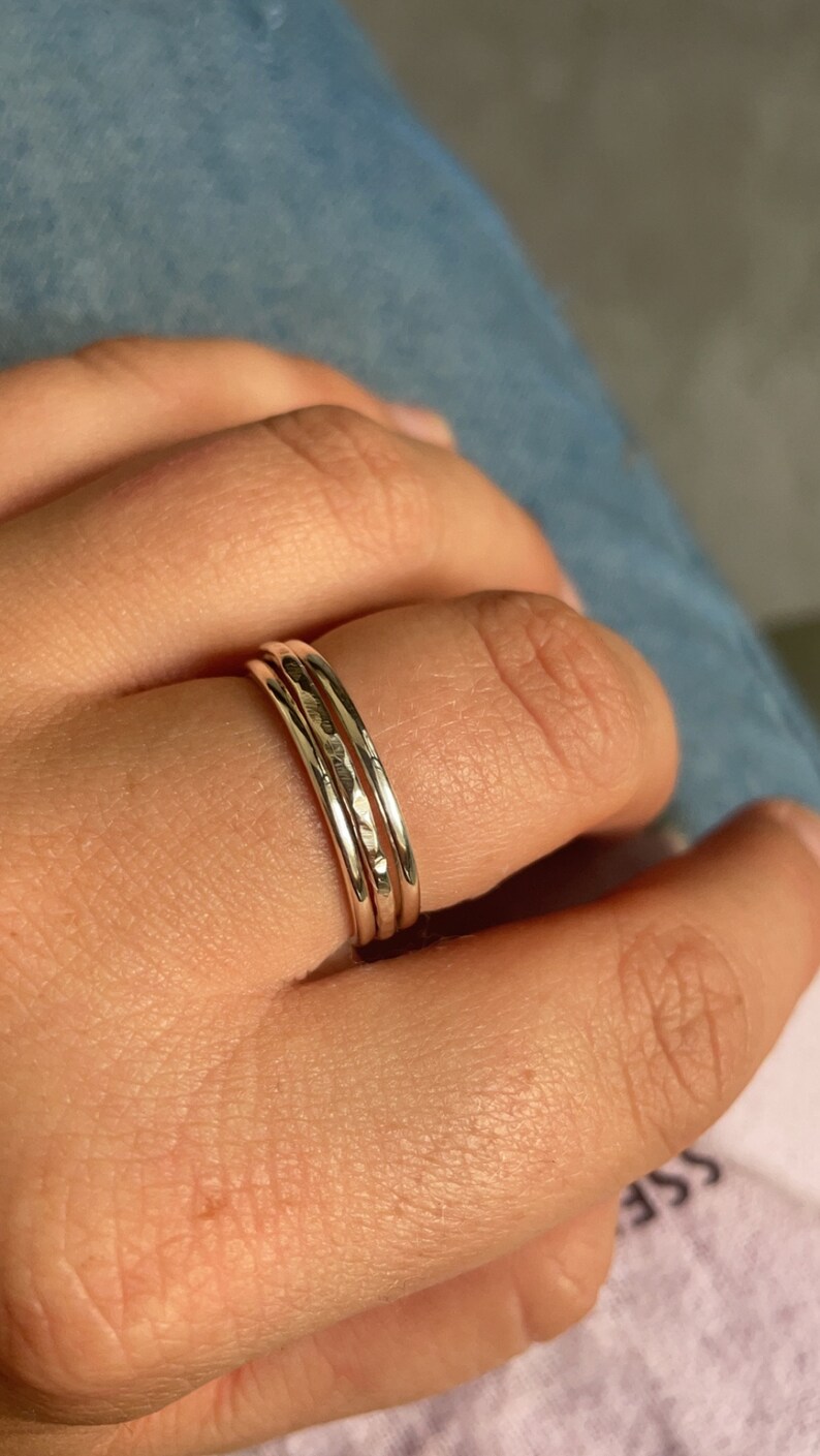 Pode incluir: Tr&ecirc;s an&eacute;is finos de prata empilhados em um dedo. Os an&eacute;is t&ecirc;m uma textura martelada.