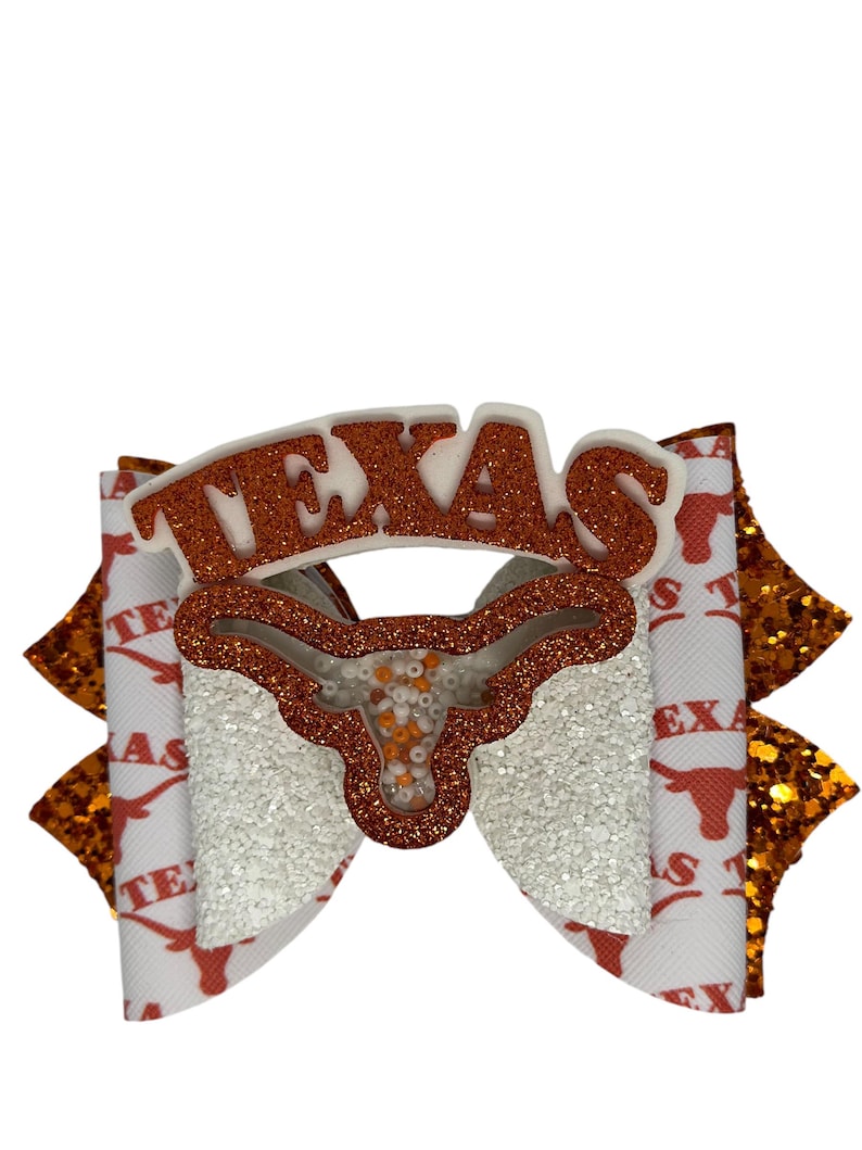 May include: White and orange glitter bow with a white "TEXAS" cutout and a white and orange glitter Longhorn head cutout.