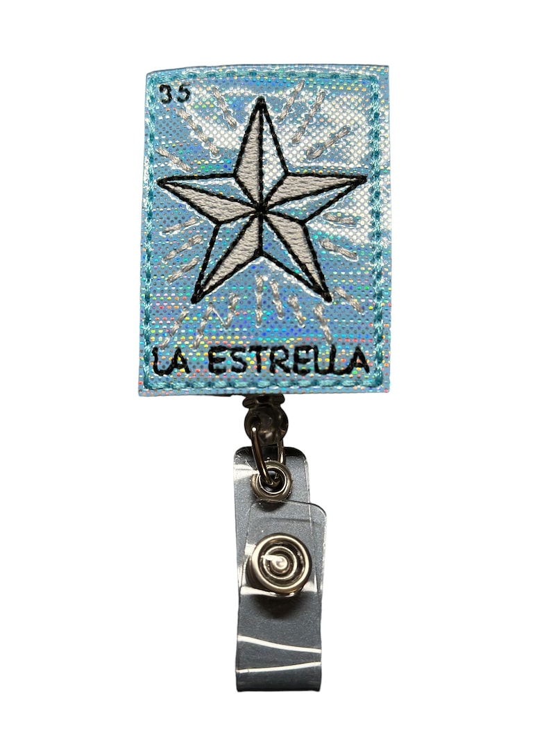 May include: A blue and silver badge holder with a white star and the text "LA ESTRELLA" on the front. The badge holder has a retractable clip.