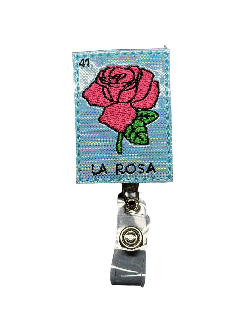 May include: A blue and silver holographic badge holder with a pink embroidered rose and the text "LA ROSA" and the number "41".