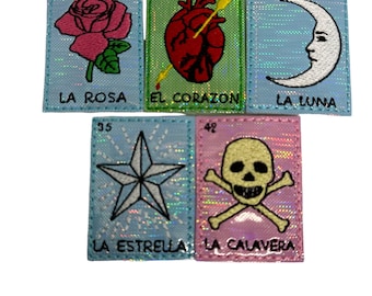 May include: Five colourful embroidered patches featuring images of a rose, heart with an arrow, crescent moon, star, and skull and crossbones. Each patch has a number and Spanish text, including "La Rosa", "El Corazon", "La Luna", "La Estrella", and "La Calavera".