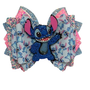 May include: A layered hair bow featuring a blue glitter Stitch character. The bow has layers of pink, blue, and glittery materials. The base layer has a light blue pattern with Stitch illustrations.