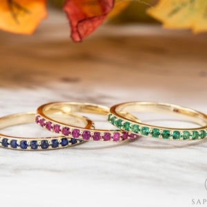 Peut inclure: Trois bagues en or avec une rangée de pierres précieuses. La bague du haut a des pierres précieuses vertes, la bague du milieu a des pierres précieuses roses et la bague du bas a des pierres précieuses bleues.