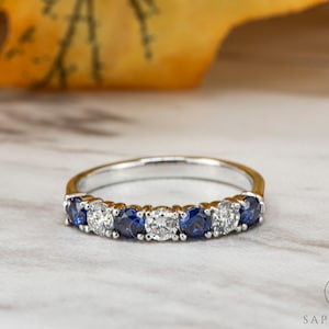 Peut inclure: Une bague en argent avec des saphirs bleus et des diamants clairs alternés.