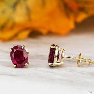 Peut inclure: Une paire de boucles d'oreilles en or avec des pierres précieuses rubis de forme ovale. Les boucles d'oreilles ont un design simple et sont parfaites pour tous les jours.