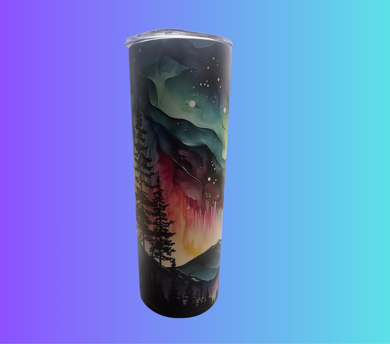 May include: A stainless steel tumbler with a clear lid. The tumbler has a watercolour design of a night sky with the aurora borealis, mountains, and trees. The colours include shades of blue, green, red, and black.