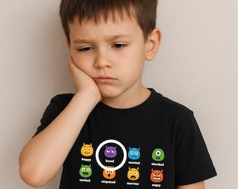 Könnte beinhalten: Ein Kind trägt ein schwarzes T-Shirt mit Cartoon-Gesichtern, die verschiedene Emotionen darstellen. Das Wort "bored" ist hervorgehoben. Das Kind berührt seine Wange und wirkt gelangweilt. Das Design umfasst weitere Emotionen.
