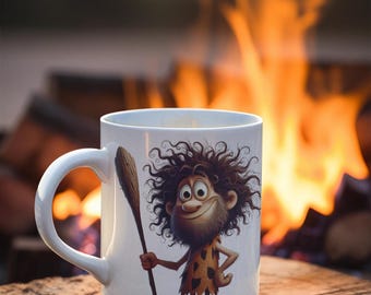 May include: White ceramic mug with a cartoon illustration of a caveman holding a stick. The caveman has brown hair, a beard, and is wearing a brown loincloth. The mug is in front of a blurry background of a campfire.