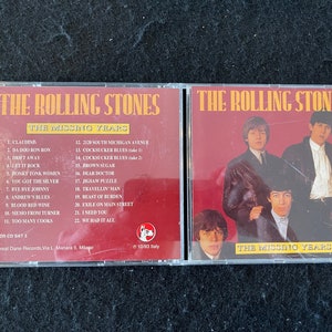 May include: A red and white CD case featuring a picture of The Rolling Stones on the front. The album title is "The Missing Years" and the track listing is printed on the back of the case.